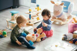 Two children playing together with a stuffed animal demonstrating what is social skills training